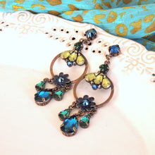 Decorative earrings with blue and green stones on a decorative surface

