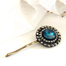 Hairpin with blue gemstone and gold accents on a white background

