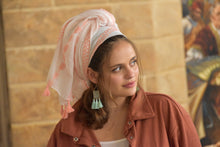 Woman wearing a headscarf and earrings with a blurred background

