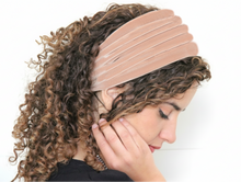 Woman wearing a beige headband with curly hair on a white background

