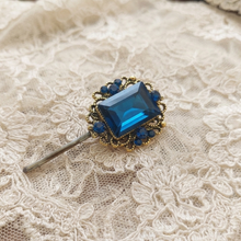 Blue gemstone brooch on a lace fabric background

